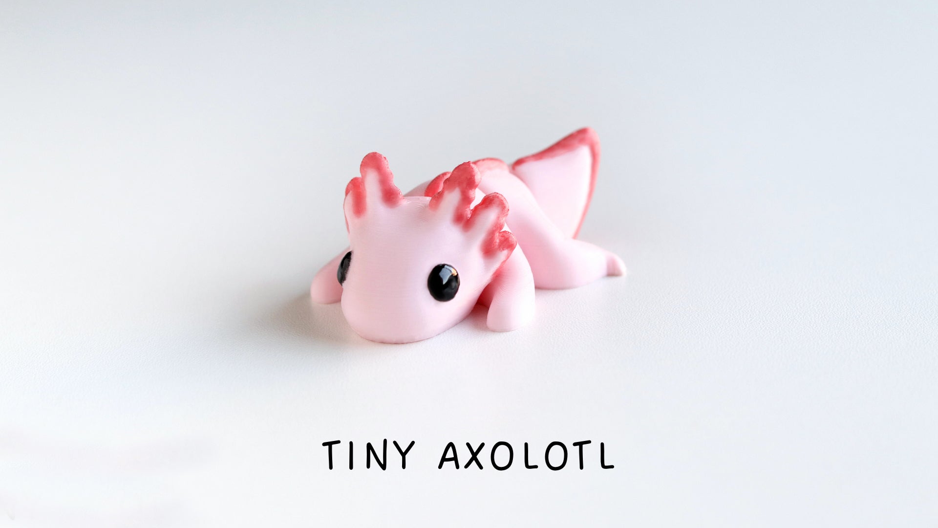 a tiny pink toy with black eyes laying on a white surface