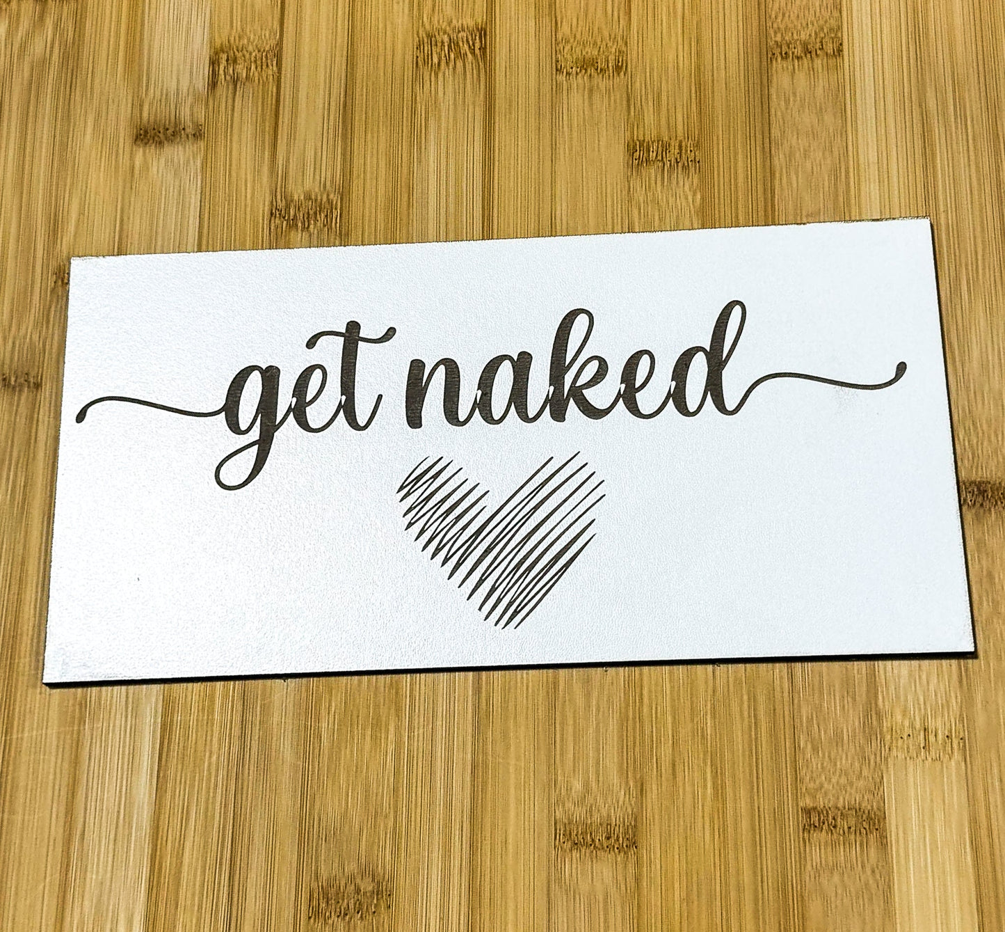 a sticker that says get naked on a wooden surface