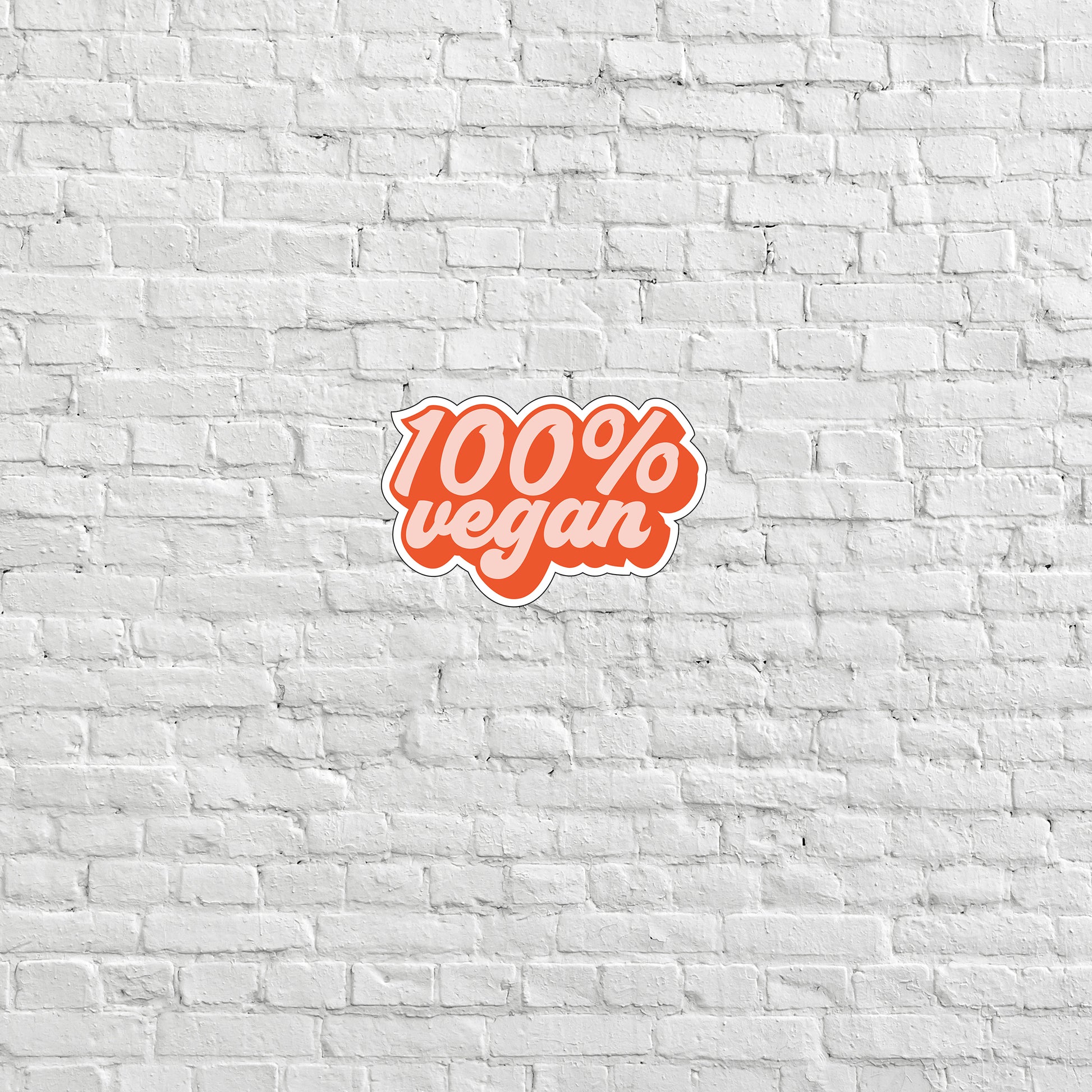 a white brick wall with a red sticker that says 100 % vegan